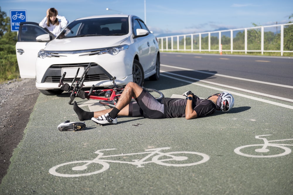 Cyclist Has Been Hit By A White Car And Is Laying On The Ground