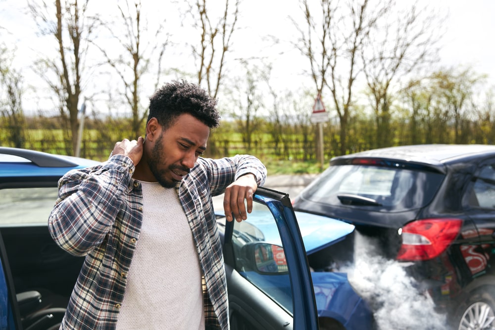 A Man Holding His Neck In Pain After A Car Accident