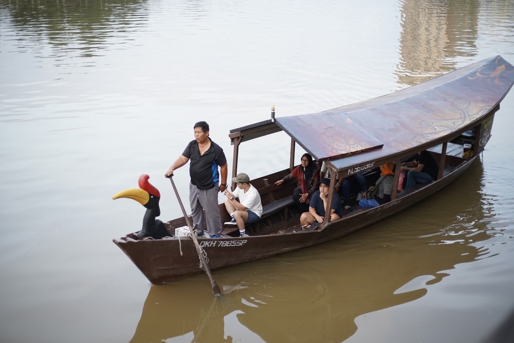 Boatman Steering A Boat With Passengers