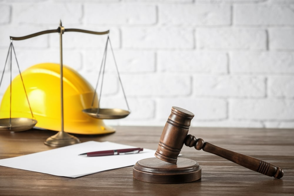 Judges Hammer With Scales And Yellow Helmet On A Table