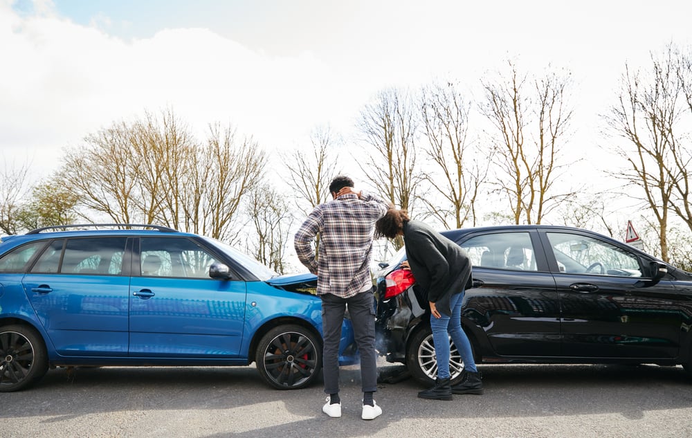Vehicle owners inspecting a rear end car accident of their blue and black cars