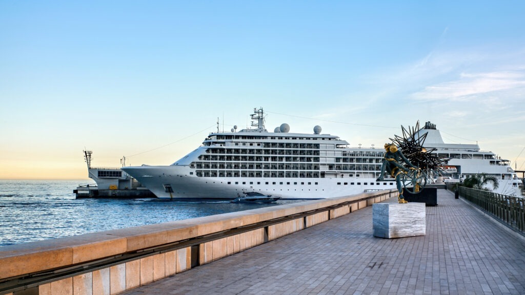 Cargo ferry ship with loaded cars A cruise ship with a parked red car.
